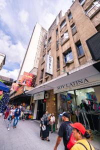 Un groupe de personnes marchant dans une rue en face d'un magasin dans l'établissement HOTEL CALLE REAL SUITE, à Medellín