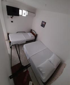 Habitación pequeña con 2 camas y TV. en Rivera Hostel, en Santa Marta