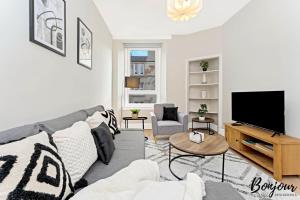 a living room with a gray couch and a flat screen tv at Mabillon Suite - Gorgeous-Haymarket, City Centre-FREE Parking by Bonjour Residences Edinburgh in Edinburgh