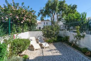 eine Terrasse mit zwei weißen Bänken in einem Garten in der Unterkunft Casa Caravela, Praia da Luz in Luz