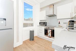 a kitchen with white cabinets and a window at Mabillon Suite - Gorgeous-Haymarket, City Centre-FREE Parking by Bonjour Residences Edinburgh in Edinburgh