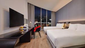 ein Hotelzimmer mit 2 Betten und einem Schreibtisch mit einem TV in der Unterkunft Holiday Inn Express Taichung Park, an IHG Hotel in Taichung