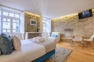 a bedroom with a bed and a stone wall at PWHC Miragaia Apartments in Porto