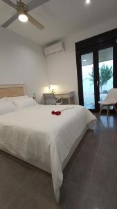 een slaapkamer met een wit bed met een rode bloem erop bij Chalet con piscina y jardín, no fumadores ni fiestas in Cúllar-Vega