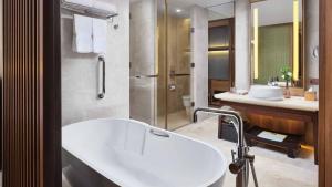 Crowne Plaza Hailing Island, an IHG Hotel في يانغجيانغ: حمام مع حوض أبيض ومغسلة