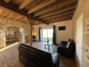 a living room with leather furniture and a stone wall at Gîte Ygrande, 4 pièces, 8 personnes - FR-1-489-433 in Ygrande