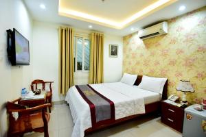 een slaapkamer met een bed, een bureau en een televisie bij Hotel Thu Ha - Sân bay Tân Sơn Nhất in Ho Chi Minh-stad