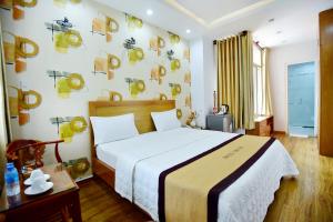 een slaapkamer met een groot bed en een muur met schilderijen bij Hotel Thu Ha - Sân bay Tân Sơn Nhất in Ho Chi Minh-stad