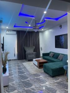 Beautiful 2Br Apt in Ogba, Ikeja, Lagos في لاغوس: غرفة معيشة مع أريكة خضراء وطاولة
