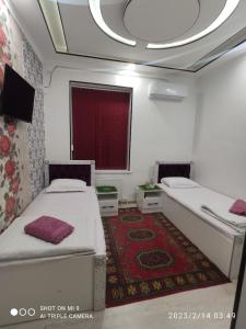 a room with two beds and a red carpet at KAMIR Guest House in Bukhara