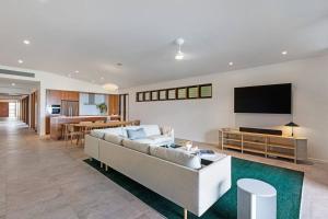 a living room with a couch and a flat screen tv at Indigo at Funnel Bay in Airlie Beach