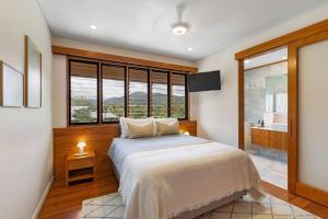 a bedroom with a large bed and a sink at Indigo at Funnel Bay in Airlie Beach