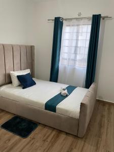 a bed sitting in a room with a window at La Maison II- Two Bedroom in Tatu City, Nairobi in Nairobi