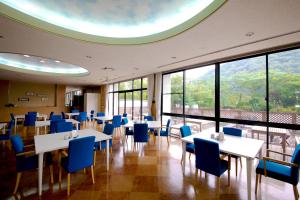 une salle à manger avec des tables, des chaises bleues et des fenêtres dans l'établissement Koderaso, à Himeji