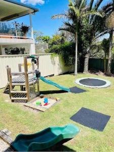 een achtertuin met een speeltuin met een glijbaan en een trampoline bij The Wreck Room Holiday House close to the Beach with Ample Boat Parking in Shoal Bay