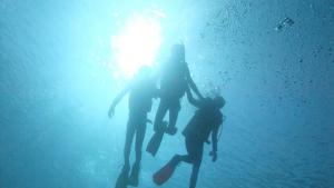 tre persone in piedi in acqua con uno skateboard di Hotel Miyuki Beach a Onna