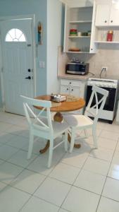 a kitchen with a wooden table and two white chairs at Lynn's Cozy Cottage in Nassau