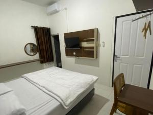 a bedroom with a bed and a desk and a tv at Nikie Guesthouse in Semarang
