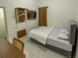 a bedroom with a bed and a tv in it at Nikie Guesthouse in Semarang