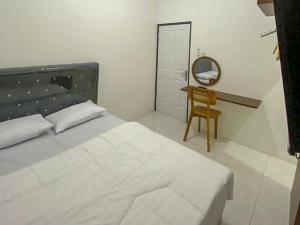 a bedroom with a bed and a desk and a mirror at Nikie Guesthouse in Semarang