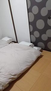 1 cama con sábanas blancas en el suelo de madera en メゾネットHIRAKU en Izumi-Sano