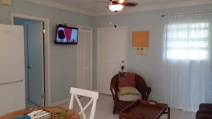 uma sala de estar com uma cadeira e uma televisão na parede em Lynn's Cozy Cottage em Nassau