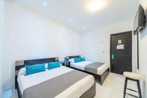 1 dormitorio con 2 camas, TV y taburete en Hotel Mar di Plata, en Barranquilla
