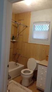 a bathroom with a toilet and a tub and a sink at Lynn's Cozy Cottage in Nassau