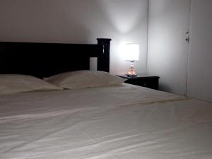 una cama con una cabecera negra y una lámpara sobre una mesa en Room in House - Taminaka Hostel en Santa Marta - Shared room 3, en Santa Marta