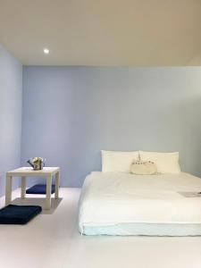 南竿鄉的住宿－三隻腳民宿，白色的卧室配有白色的床和一张桌子