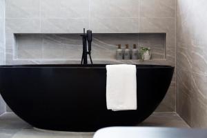 a black tub in a bathroom with a white towel at Villa L3 by Stay Samui - Bohemian Chic in Koh Samui 