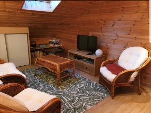 uma sala de estar com cadeiras de vime e uma televisão de ecrã plano em Chalet Bois Cosy em Ferdrupt