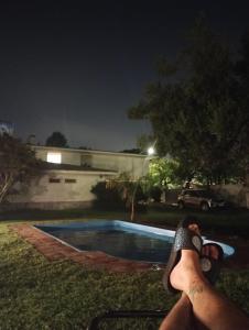 a person with their feet up next to a swimming pool at night at Departamento privado en Casa Barranca Yaco in Córdoba