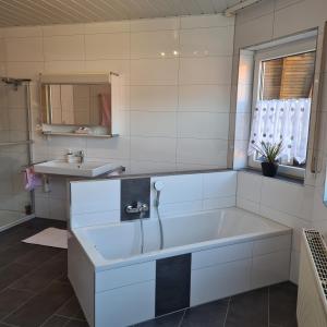 a white bathroom with a tub and a sink at Ferienwohnung Cornelia und Michael Persang GbR in Eppenbrunn