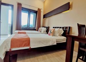 a bedroom with two beds with a desk and a window at Avila Ketapan Rame Hotel in Trawas