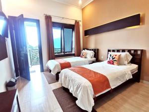 a hotel room with two beds and a window at Avila Ketapan Rame Hotel in Trawas
