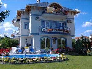 une grande maison blanche avec une piscine en face de celle-ci dans l'établissement Judit haus, à Balatonfüred