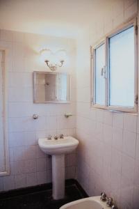 baño blanco con lavabo y ventana en Casa Compartida Barranca Yaco - Habit privadas en Córdoba
