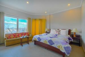 ein Schlafzimmer mit einem Bett, einem Sofa und einem Fenster in der Unterkunft SaffronStays Sherni House, Mashobra in Mashobra