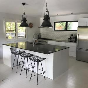 a kitchen with a large island with stools at Palm Springs Vibe - Gorgeous Large Home, Superb Location in Noosa Heads
