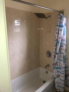 ein Badezimmer mit einer Badewanne mit Duschvorhang in der Unterkunft Hidden Escape,pool,gated,gym,air-conditioned, in Mammee Bay