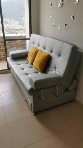 um sofá cinzento com duas almofadas amarelas num quarto em Duplicado Beautiful 25th floor apartment em Bello