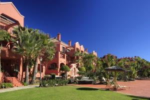 ein Gebäude mit Palmen und einem Rasen davor in der Unterkunft Vasari Resort in Marbella