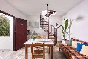 a living room with a table and a spiral staircase at Eva Suites & Apartments in Agia Marina Nea Kydonias