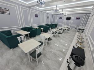 um restaurante com cadeiras verdes e mesas e mesas e cadeiras em OLD STATION HOTEL em Samarkand