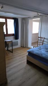 1 Schlafzimmer mit einem Bett, einem Schreibtisch und 2 Fenstern in der Unterkunft Mini Happy home in Reconvilier