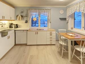 une cuisine avec des placards blancs, une table et une salle à manger dans l'établissement Holiday home STONGLANDSEIDET II, à Stonglandseidet