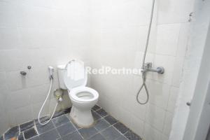 La salle de bains est pourvue d'une douche et de toilettes. dans l'établissement Katup Guest House Syariah Mitra RedDoorz, à Yogyakarta