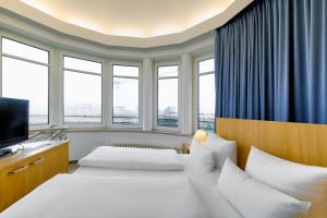 a hotel room with two beds and windows at Hotel Berlin Mitte by Campanile in Berlin