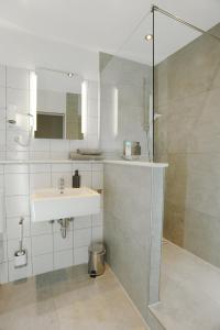 een witte badkamer met een wastafel en een douche bij Swetis Passage in Pulheim